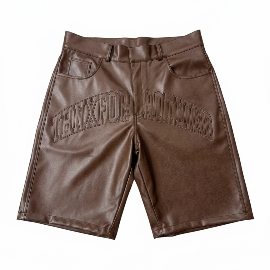 Brown faux leather shorts with a debossed 'THENXFOR NOTHING' logo across the front, displayed flat against a white background.