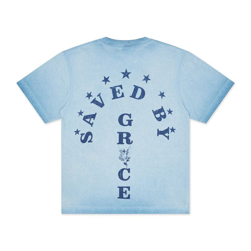 A light blue short-sleeve t-shirt with a dark blue graphic on the back featuring the words 'SAVED BY GRACE' in a circular arch with stars and a rose design.