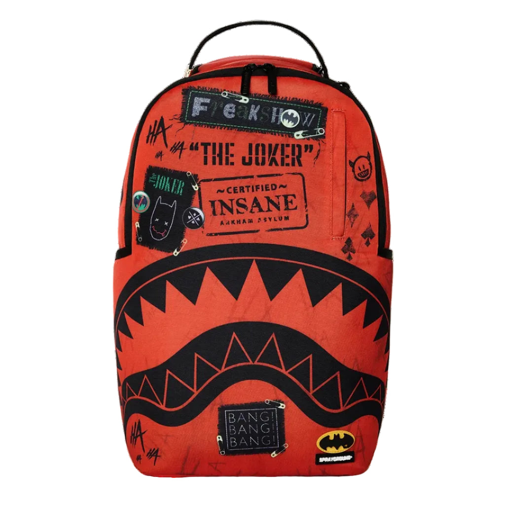 A bright orange-red backpack featuring a black shark mouth graphic across the lower half, with distressed patches and text including 'F*CK YOU', 'THE JOKER', 'INSANE', and Batman logos, shown on a white background.