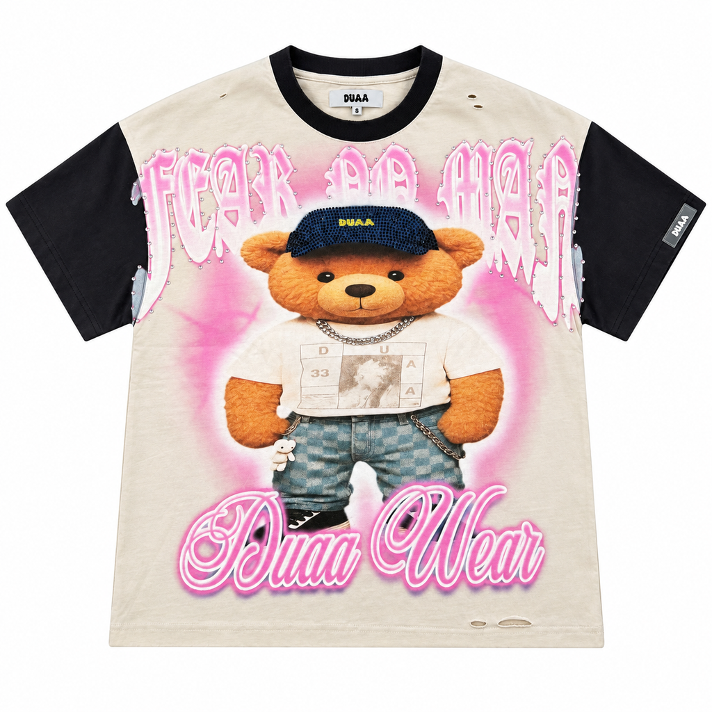A Fear of God x Dina Wear collaboration t-shirt featuring a beige body, black sleeves, and a central graphic of a teddy bear wearing a blue cap and jeans, surrounded by pink 'FEAR OF GOD' and 'Dina Wear' text.