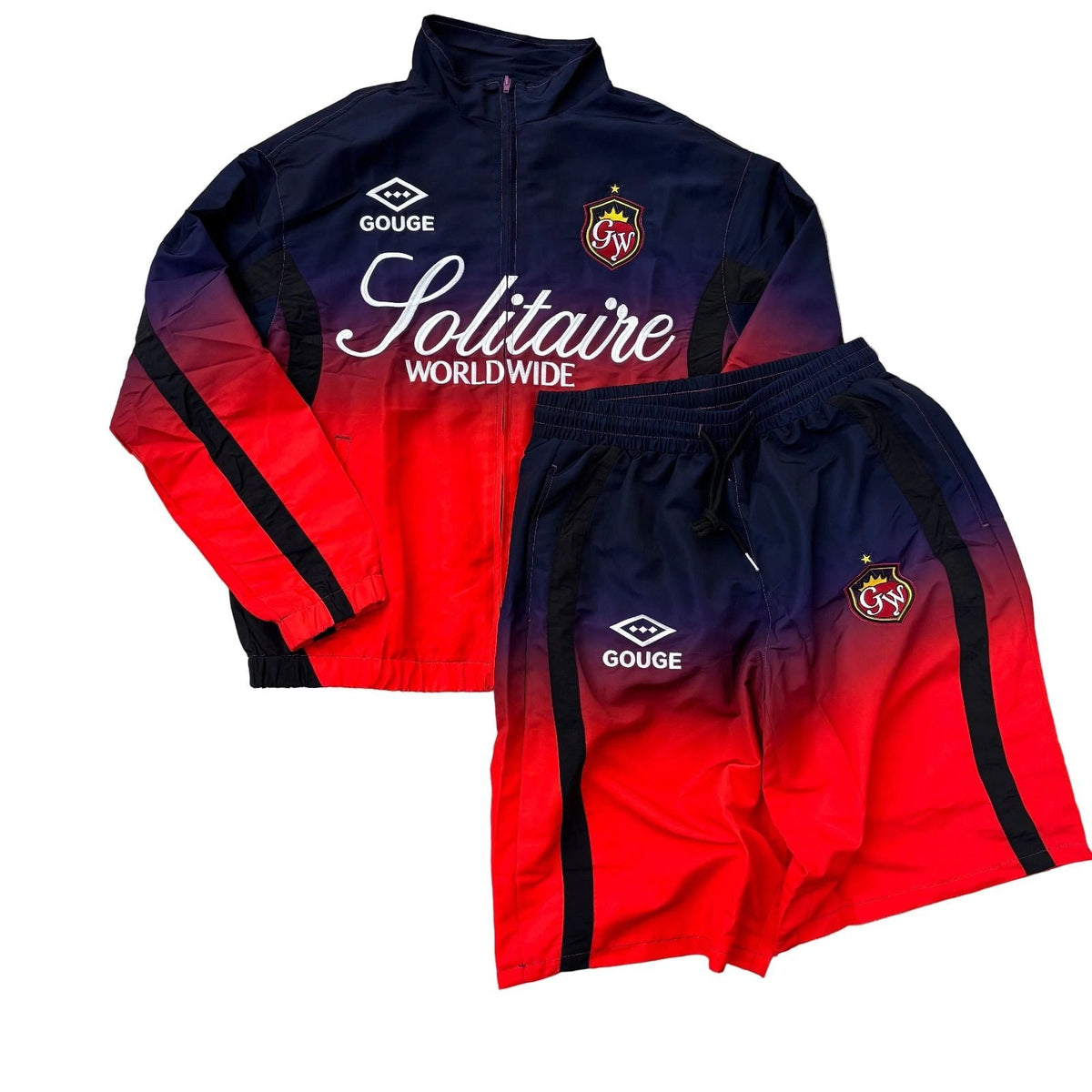 A vintage soccer tracksuit set from 2015 by Gouge and Solitaire Worldwide, featuring a zip-up jacket and matching shorts with a navy-to-red gradient and black side stripes, laid flat on a gray stone background.
