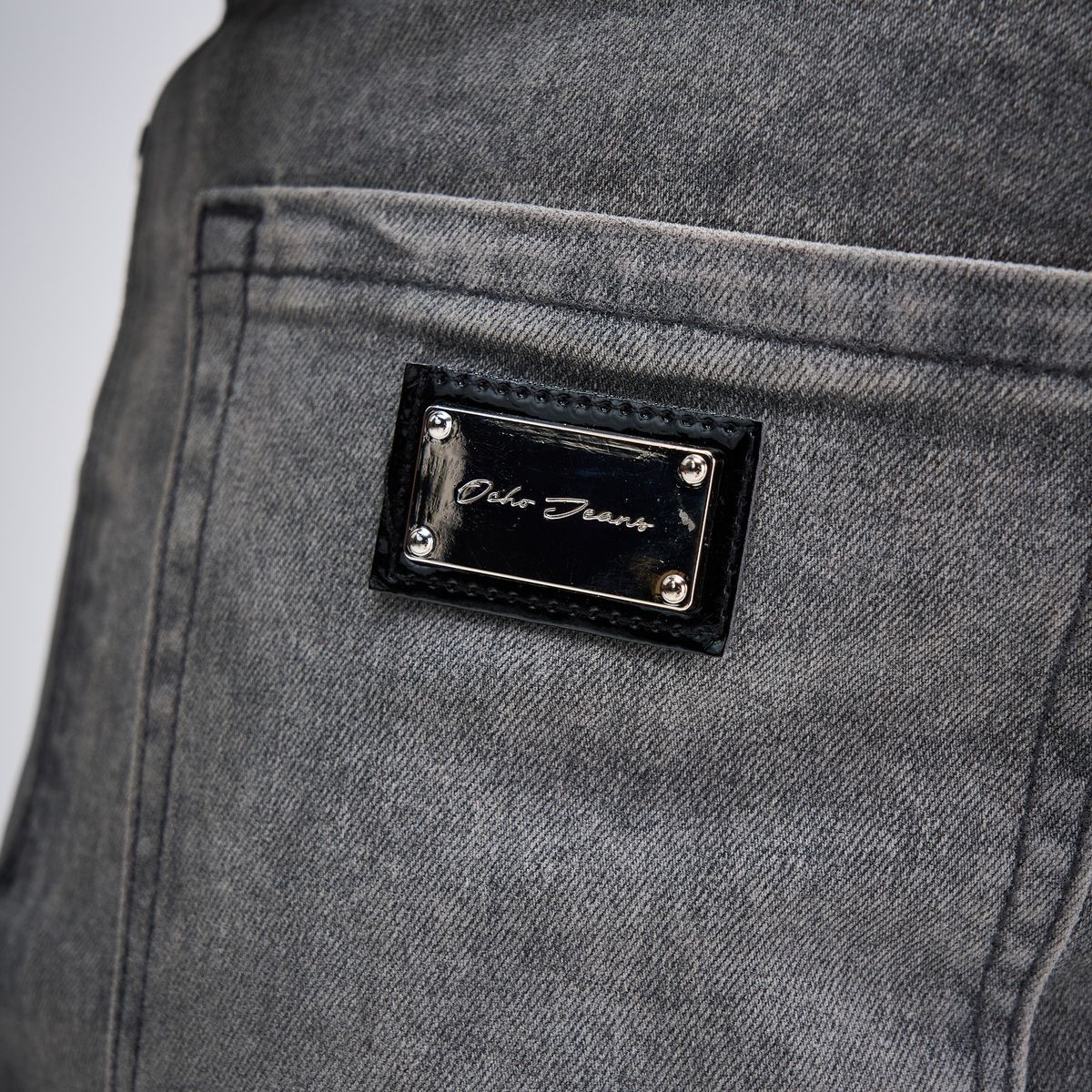 OCHO DUSK dark gray jeans, engraved rear-pocket metal plate on stitched black backing